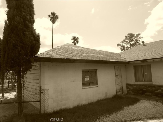view of side of property featuring roof with shingles and concrete block siding