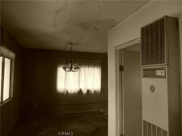 unfurnished dining area featuring a notable chandelier, a textured ceiling, and a heating unit
