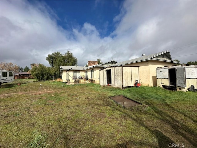 back of property with an outdoor structure, a shed, and a yard
