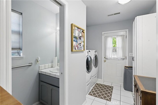 washroom with washer and clothes dryer, laundry area, visible vents, light tile patterned floors, and baseboards