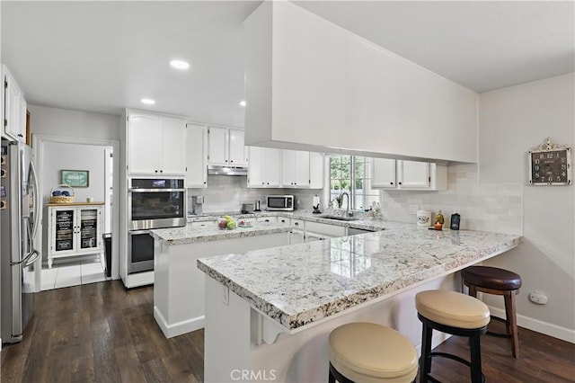 3571 White Wolf Ct, Merced, CA 95340 - kitchen featuring appliances with stainless steel finishes, a sink, a peninsula, dark wood-style flooring, and tasteful backsplash
