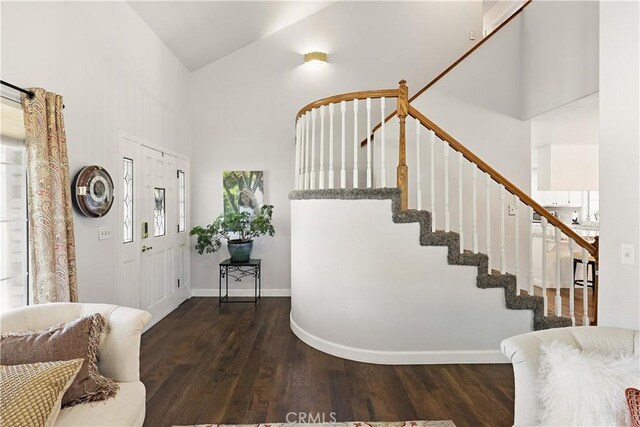 entryway with high vaulted ceiling, wood finished floors, baseboards, and stairs