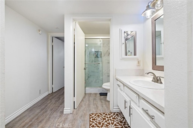 full bath featuring vanity, toilet, a marble finish shower, and wood finished floors