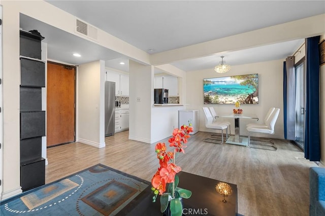 living room with visible vents, light wood-style floors, baseboards, recessed lighting, and a chandelier