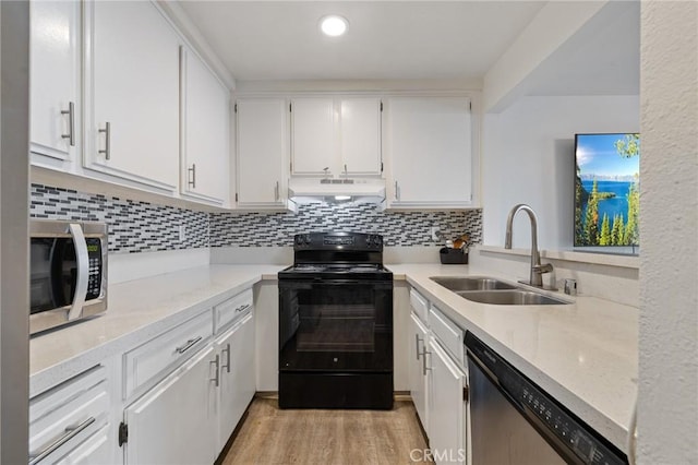 kitchen featuring appliances with stainless steel finishes, a sink, white cabinets, light wood finished floors, and under cabinet range hood