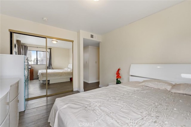 bedroom with visible vents, baseboards, wood finished floors, and a closet