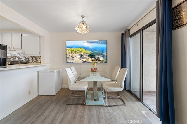 dining area with baseboards, a chandelier, and light wood-style floors