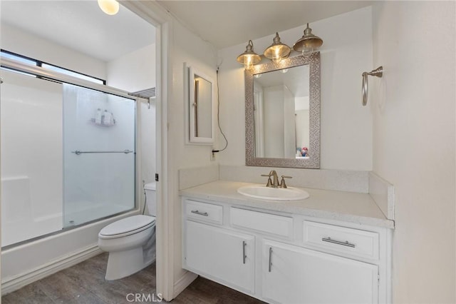 full bath with vanity, combined bath / shower with glass door, toilet, and wood finished floors