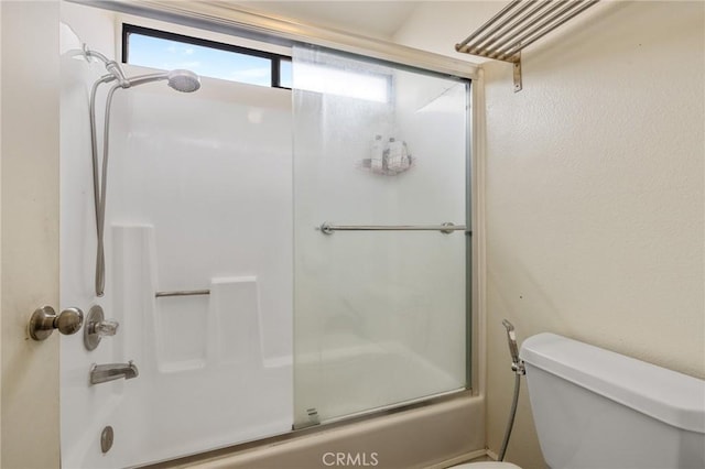 bathroom featuring combined bath / shower with glass door and toilet