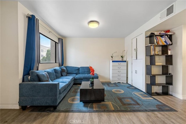 living room featuring baseboards, visible vents, and wood finished floors