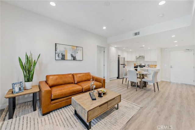 living room featuring recessed lighting, baseboards, visible vents, and light wood-style flooring