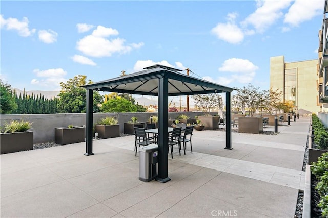 view of property's community with fence, outdoor dining space, a gazebo, and a patio area