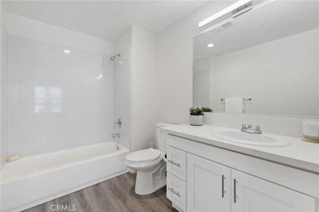 bathroom with visible vents, vanity, wood finished floors, toilet, and shower / washtub combination