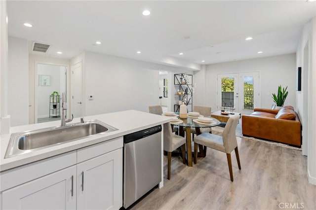 kitchen featuring a sink, dishwasher, light wood-style flooring, white cabinetry, and visible vents
