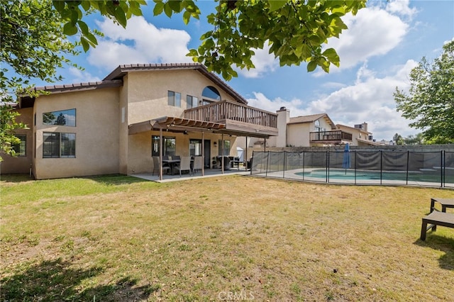 back of property featuring fence, a fenced in pool, stucco siding, and a lawn