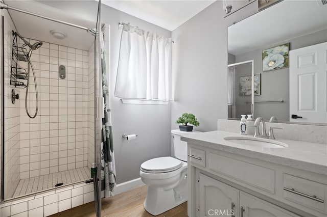 bathroom with vanity, a shower stall, toilet, and wood finished floors