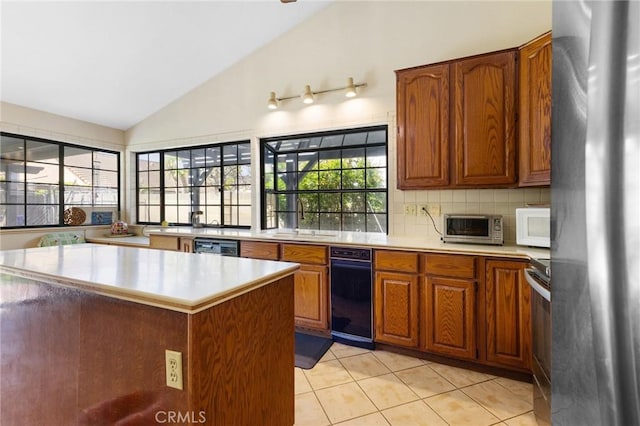 kitchen with brown cabinets, light tile patterned flooring, appliances with stainless steel finishes, a sink, and light countertops