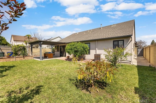 back of property featuring a shingled roof, stucco siding, a fenced backyard, a patio area, and a yard