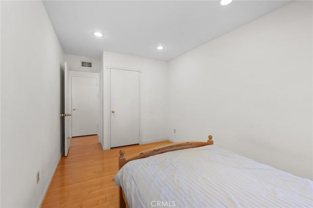 bedroom with light wood finished floors, recessed lighting, baseboards, visible vents, and a closet