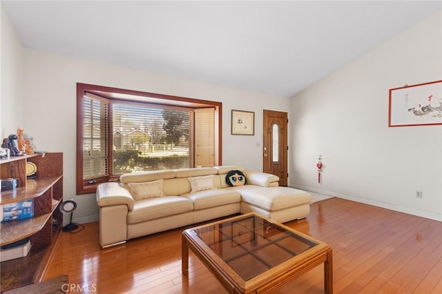 living room featuring baseboards, wood-type flooring, and vaulted ceiling