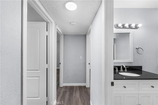 10341 N Loop Blvd, California City, CA 93505 - bathroom with baseboards, a textured ceiling, wood finished floors, and vanity