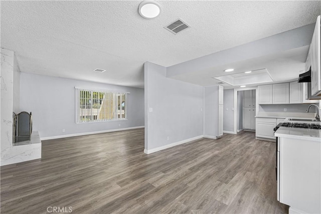 10341 N Loop Blvd, California City, CA 93505 - unfurnished living room with dark wood-style flooring, a textured ceiling, baseboards, a tray ceiling, and visible vents