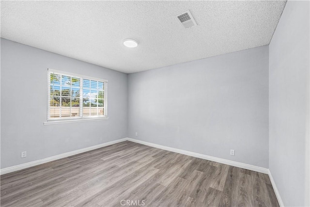10341 N Loop Blvd, California City, CA 93505 - empty room with baseboards, a textured ceiling, visible vents, and wood finished floors