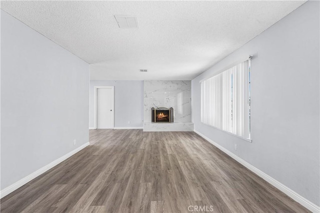 10341 N Loop Blvd, California City, CA 93505 - unfurnished living room featuring a high end fireplace, baseboards, a textured ceiling, and wood finished floors