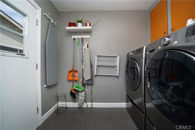 washroom featuring baseboards, cabinet space, and washing machine and clothes dryer
