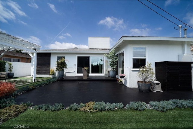 rear view of property with a pergola, a patio area, and stucco siding