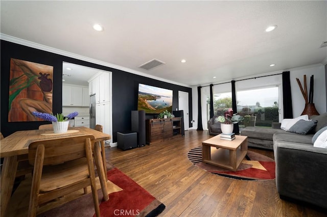 living area with crown molding, wood finished floors, and visible vents