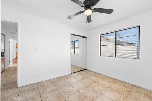 unfurnished bedroom with baseboards, ceiling fan, light tile patterned floors, and a closet