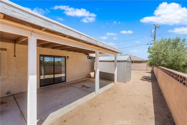 view of patio with a storage unit, a fenced backyard, and an outbuilding