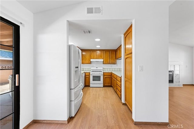kitchen featuring visible vents, white appliances, light wood-type flooring, light countertops, and brown cabinets