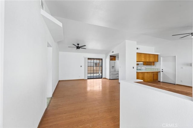 unfurnished living room with visible vents, lofted ceiling, baseboards, a ceiling fan, and light wood-style flooring