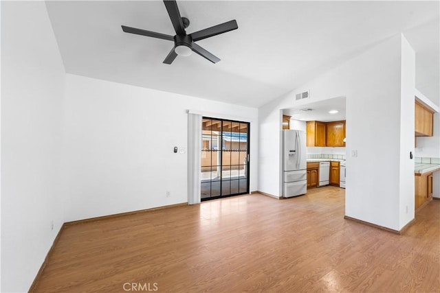 unfurnished living room featuring ceiling fan, baseboards, lofted ceiling, light wood-type flooring, and visible vents