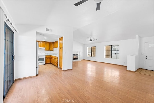 unfurnished living room with light wood-style floors, a ceiling fan, baseboards, and a glass covered fireplace