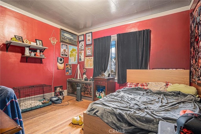 bedroom with ornamental molding and wood finished floors