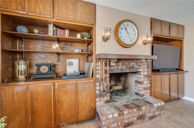 living room featuring baseboards, light tile patterned floors, and a fireplace