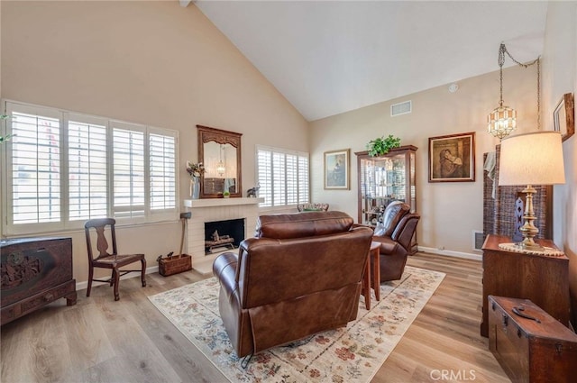 living room featuring high vaulted ceiling, visible vents, baseboards, and light wood finished floors