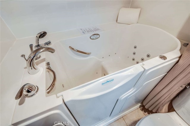 full bath with a tub with jets and tile patterned flooring