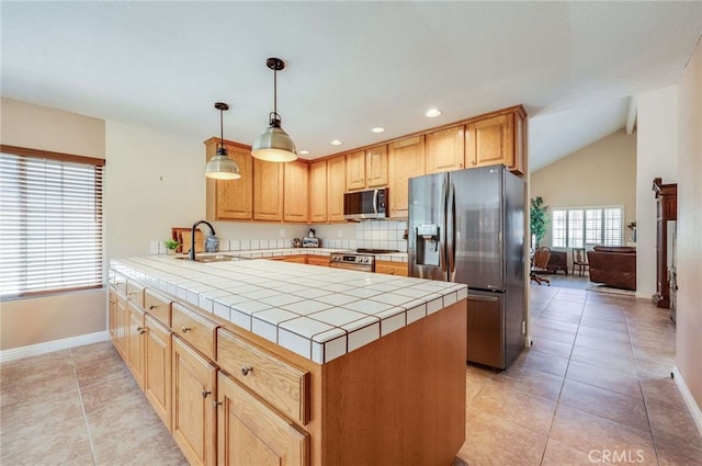 kitchen with appliances with stainless steel finishes, a sink, tile counters, a peninsula, and baseboards