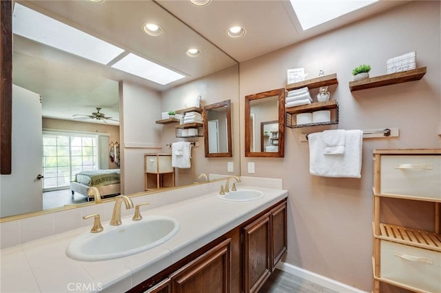 full bath featuring connected bathroom, recessed lighting, a skylight, and a sink