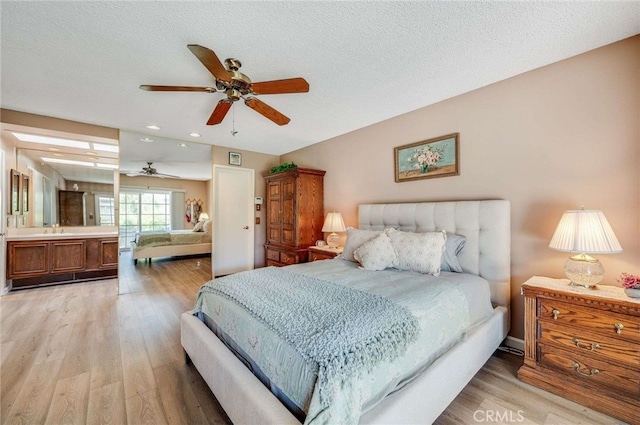 bedroom with light wood-style floors, baseboards, recessed lighting, a textured ceiling, and a sink