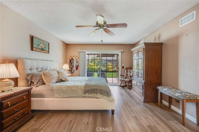 bedroom with access to outside, light wood-style flooring, a textured ceiling, and visible vents