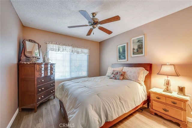 bedroom featuring a textured ceiling, baseboards, a ceiling fan, and wood finished floors
