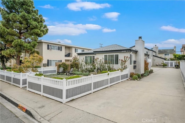 view of front of home featuring a chimney, fence private yard, and stucco siding