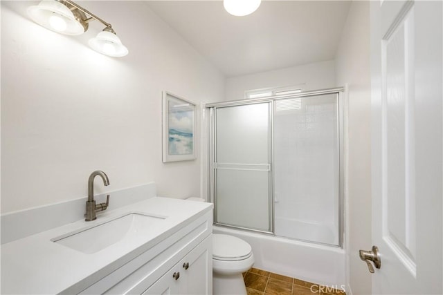 bathroom with vanity, enclosed tub / shower combo, and toilet