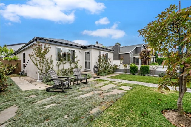back of house featuring fence, stucco siding, entry steps, a patio, and a yard