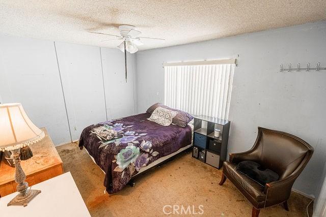bedroom with a ceiling fan, carpet, a closet, and a textured ceiling